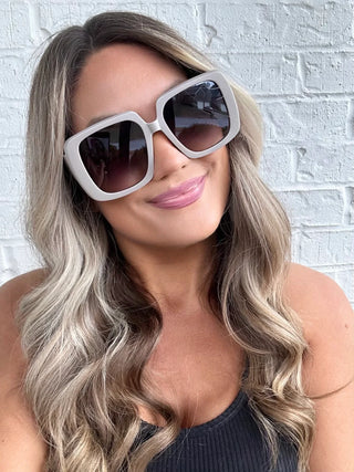 Model wearing Bora Bora Babe Sunglasses with beachy waves and a carefree summer vibe in taupe.