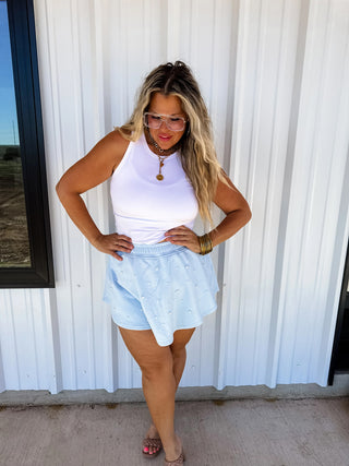 Model wearing blue pearl-embellished skort with elastic waistband and flowy skirt overlay.