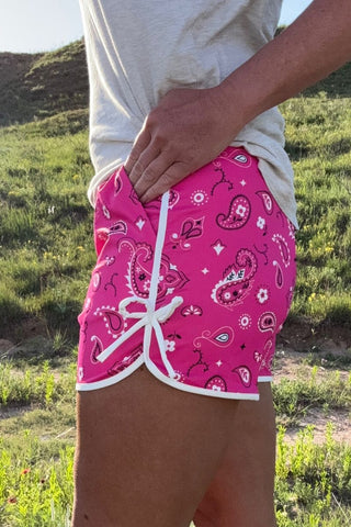 Person wearing pink bandana-patterned shorts in a natural setting