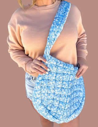 Blue Ditsy Floral Quilted Bag with a charming floral print, secure zipper closure, water-resistant inner lining, multiple pockets, and a comfortable shoulder strap—perfect for everyday use or travel.