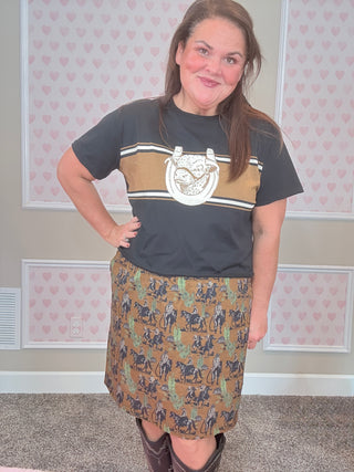 Person wearing a graphic t-shirt and western patterned skirt in a room with heart designs on the walls.