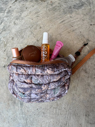 Camouflage-patterned pouch with cosmetic items on a concrete surface