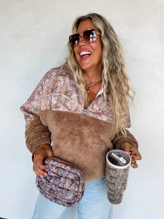 Woman holding a patterned bag and tumbler against a white background
