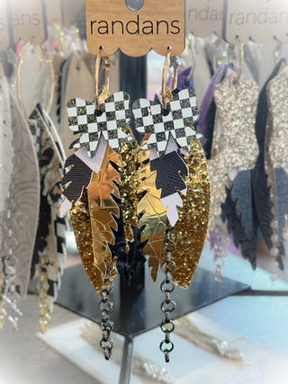 Decorative earrings with checkered and metallic designs on a 'randans' branded stand.