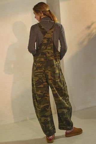 Person wearing camouflage overalls against a plain background