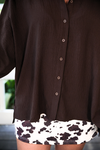 Brown shirt with a cow print hemline against a blurred background