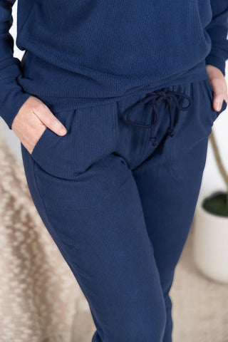 Close-up of ribbed fabric texture and drawstring waistband on navy joggers, highlighting soft, stretchy material and functional details.