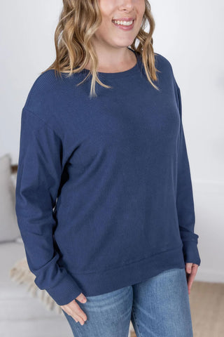 Close-up image highlighting the ribbed texture and rich navy color of the Corrine Pullover. Shows soft, stretchy fabric and stitching detail near the neckline and shoulder.