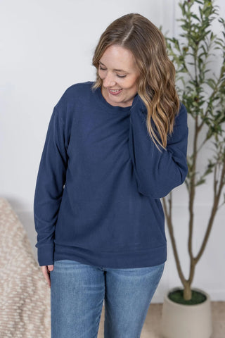 Close-up image highlighting the ribbed texture and rich navy color of the Corrine Pullover. Shows soft, stretchy fabric and stitching detail near the neckline and shoulder.