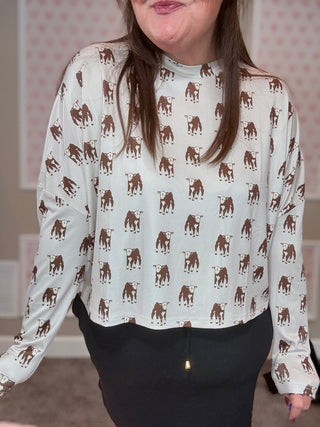 Person wearing a white blouse with brown calf pattern indoors.