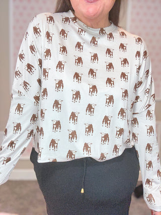 Person wearing a white long-sleeve shirt with brown calves pattern and dark skort.