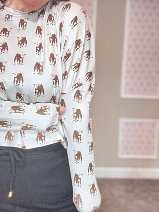 Person wearing a white long-sleeve shirt with brown cow print and dark skort.