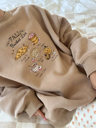 Beige sweatshirt with autumn-themed graphics on a light background