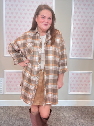 Woman wearing a plaid flannel over denim skirt with a neutral background