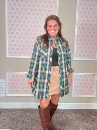 Person wearing a green plaid flannel with beige ribbed skort in a room with patterned wallpaper.