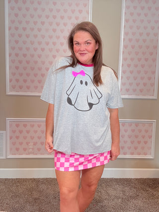 Person wearing a gray sweatshirt with a cartoon design and pink shorts in a room.