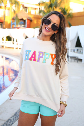 Model wearing the Happy Patch Pullover featuring ribbed cuffs, side slits, and playful patch detail.