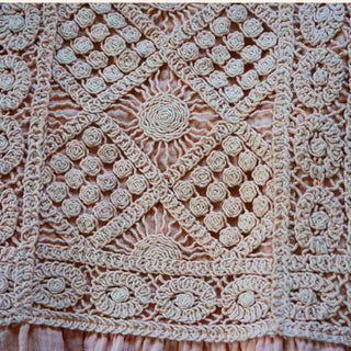 Close-up of intricate crochet detailing on the bodice and soft fabric of the maxi-length skirt.