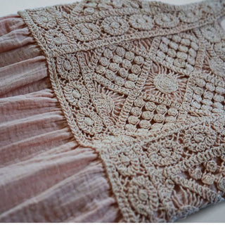 Close-up of intricate crochet detailing on the bodice and soft fabric of the maxi-length skirt.