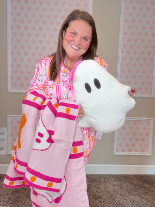 Person wearing pink pajamas holding a white plush ghost toy in a room with pink walls.