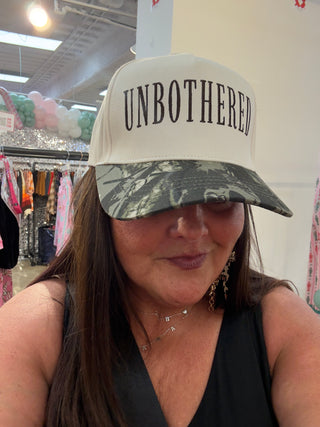 Person wearing a cap with 'UNBOtherED' text in a store setting