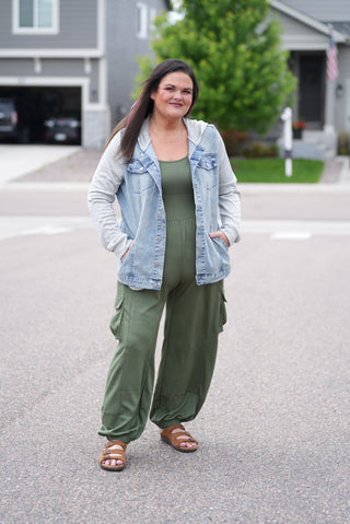 Woman wearing green pants and a light blue denim jacket outdoors.