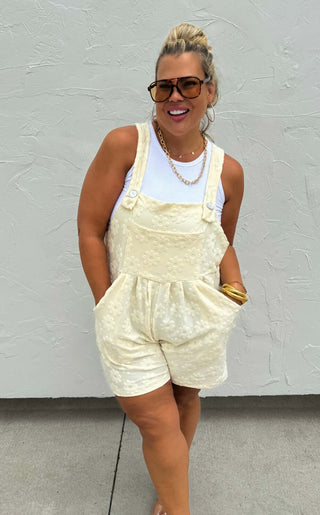 Woman wearing the Cambrie Pocket Romper, styled casually with sneakers for a relaxed, chic look.