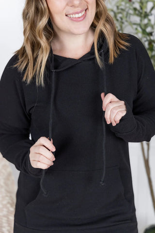 Close-up of ribbed fabric and cuffed sleeve of the Kacey Hoodie in black, with subtle texture visible.