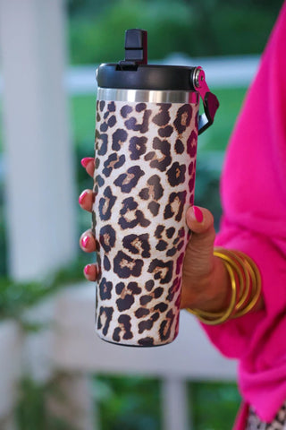 Leopard print tumbler held by a person wearing a pink top.