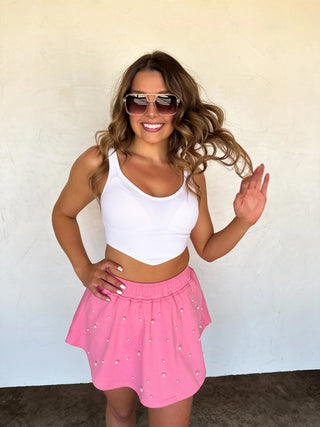 Model wearing pink pearl-embellished skort with elastic waistband and flowy skirt overlay.