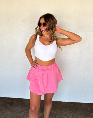 Model wearing pink pearl-embellished skort with elastic waistband and flowy skirt overlay.