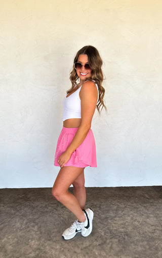 Model wearing pink pearl-embellished skort with elastic waistband and flowy skirt overlay.