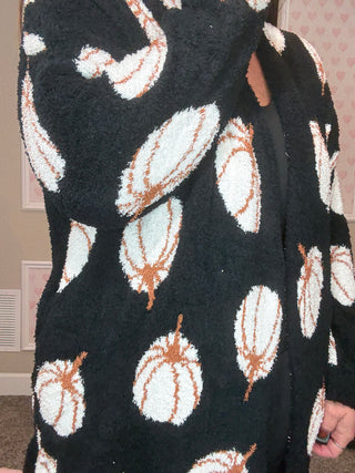Black blanket with white and brown pumpkin pattern held by a person.