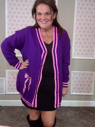 Woman wearing a purple and pink outfit with a patterned wall in the background