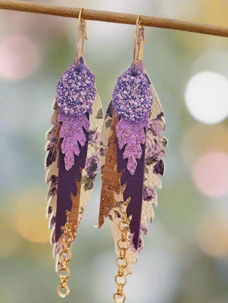 Decorative tiered earring with purple and gold elements on a blurred background