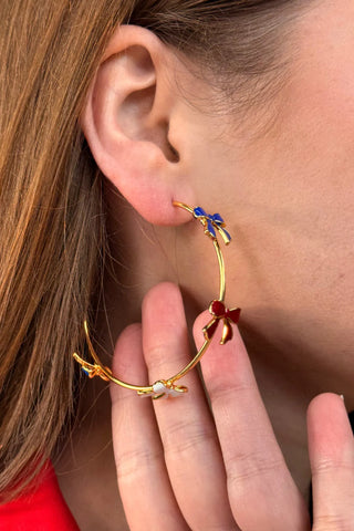 Miss Americana Hoop Earrings featuring delicate bow details on 18K gold-plated brass and steel hoops, measuring 2.25 inches—elegant, playful jewelry for any occasion.