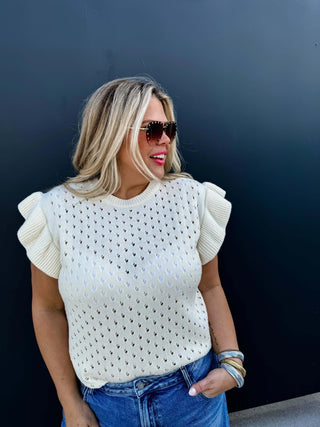 Woman wearing the Casey Ruffle Sleeve Sweater, styled casually for a chic, feminine look.