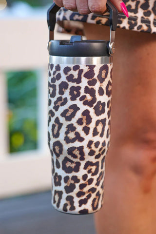 Leopard print tumbler held by a person with a blurred background