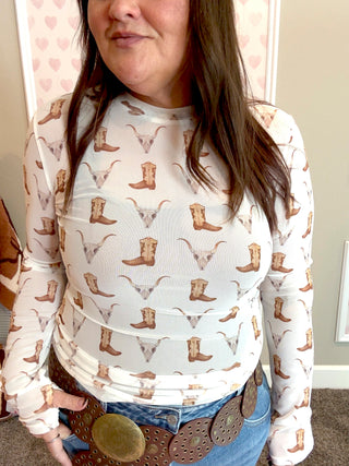 Person wearing a long-sleeve mesh shirt with skull and boot pattern in a room.