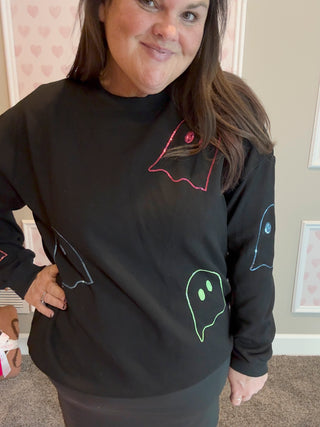 Person wearing a black sweatshirt with colorful graphics in a room.
