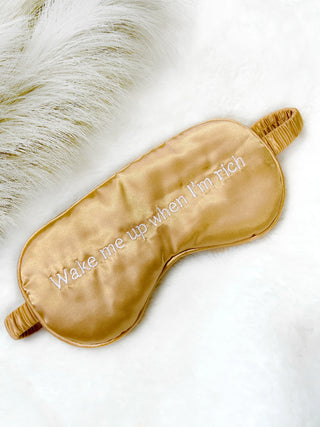 Close-up of the playful message and smooth satin fabric of the 'Wake Me Up When I’m Rich' Sleep Mask.
