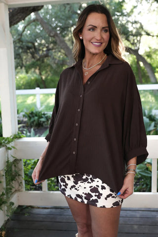 Woman wearing a brown shirt and cow print skirt outdoors