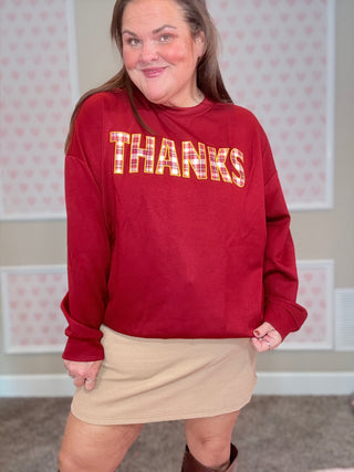 Burgundy long-sleeve pullover with plaid patch and embroidered edges — soft, stretchy fabric perfect for cozy fall outfits.