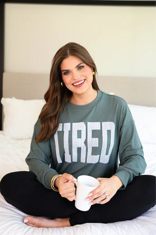 Woman wearing the Tired Embroidered Ribbed Pullover, styled casually for a cozy and fun look.