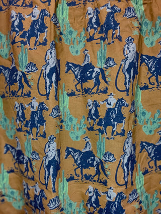 Patterned fabric with blue cowboys and horses on a mustard background