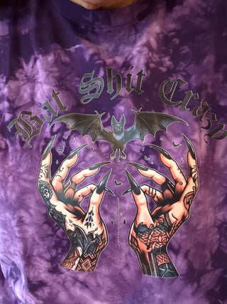 Purple tie-dye shirt with bat and hand design and text on a purple background