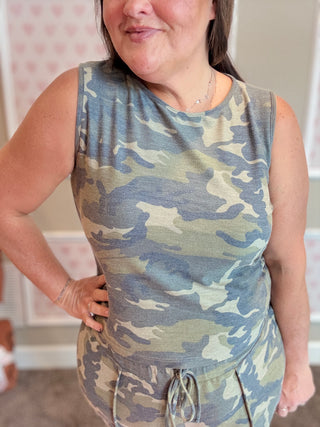 Person wearing a camouflage tank top and shorts set indoors.