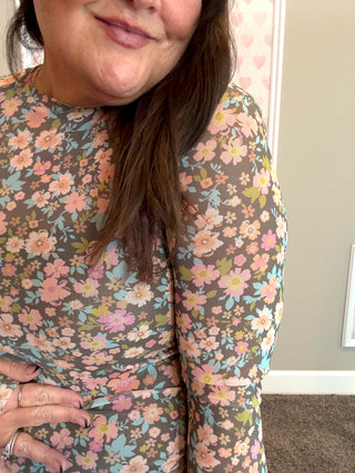 Woman wearing a floral mesh top with a neutral background