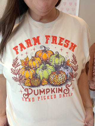 Person wearing a white t-shirt with 'Farm Fresh Pumpkins' graphic design.