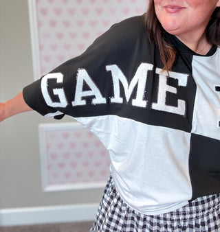 Close-up of black and white color block tee with sequin-outlined football patch, ideal for casual team spirit looks.